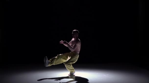 Breakdance danseur homme en pantalon jaune avec torse nu danse sur noir, ombre, ralenti — Video