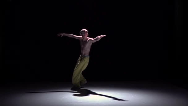 Человек-брейкдансер в желтых брюках делает стойку на руках на черном, теневом, замедленном движении — стоковое видео