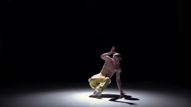 Breakdance uomo in berretto e pantaloni gialli inizia a ballare breakdance su nero, ombra, slow motion — Video Stock