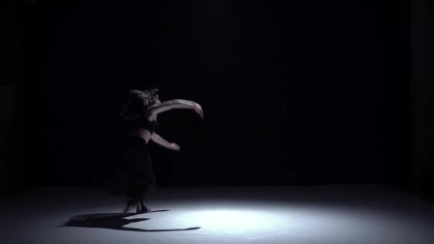 Moderne danseres meisje in donkere jurk begint dansen hedendaagse op zwart, schaduw, slow-motion — Stockvideo