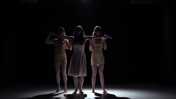 Aller sur la danse contemporaine de trois filles en robes blanches, sur noir, ombre, ralenti — Video