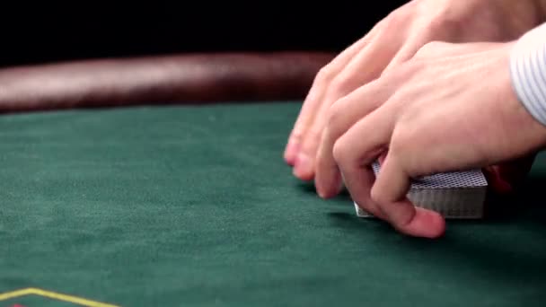 Croupier zamíchat obvyklé karty na zeleném stole v kasinu