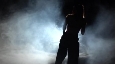 Kız karate teknikleri gösterir. Siyah. Siluet. Arka