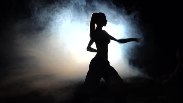Sportlerin zeigt Power-Moves schwarz. Silhouette. Gegenlicht — Stockvideo