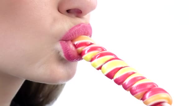 Woman licking a pink shiny lollipop on white background. Closeup