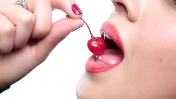 Young womans mouth with red cherries over white background. Closeup — Stockvideo