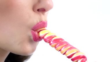 Woman licking a pink shiny lollipop. White. Close up. Slow motion