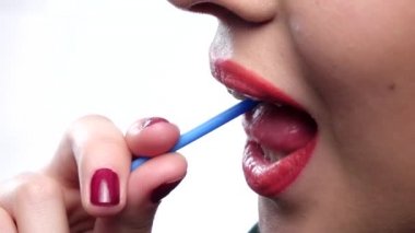 Young woman portrait with bright make up licking round sugar candy on white background. Closeup