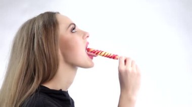Young attractive pretty excited woman eating colorful lollipop. Slow motion