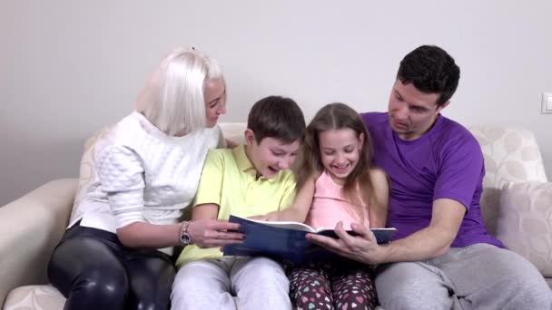 Familia feliz leyendo un libro en el sofá — Vídeos de Stock