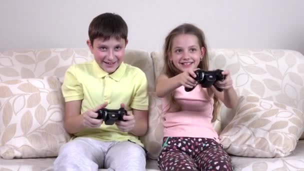 Petit frère et sœur jouant à des jeux vidéo allongés sur le canapé — Video