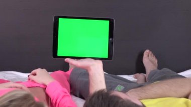 Beyaz tablet gadget, yeşil ekranda bir şey izlerken yatakta Tatlı çift