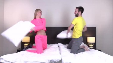 Bir yastık sahip genç mutlu çift yatakta mücadele