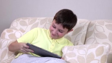 Evde tablet pc bilgisayar ile Gülümseyen küçük çocuk