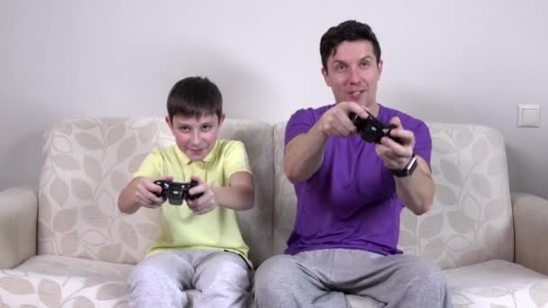 Hombre y chico joven con controladores de videojuegos sonriendo — Vídeo de stock