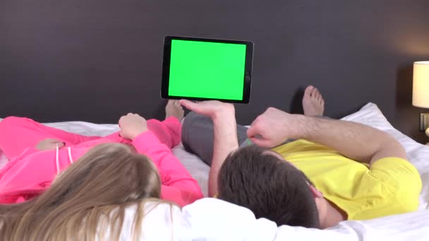 Pareja joven en la cama viendo algo en la tableta gadget, pantalla verde — Vídeo de stock