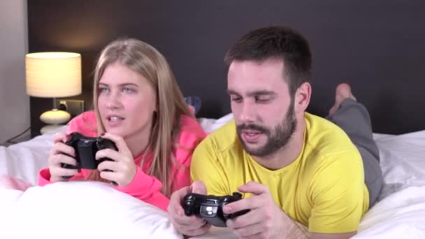 Joyeux jeune couple jouant à des jeux vidéo au lit — Video