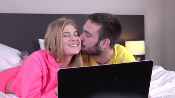 Vrolijke liefhebbers met behulp van laptop liggend op bed thuis, online winkelen — Stockvideo