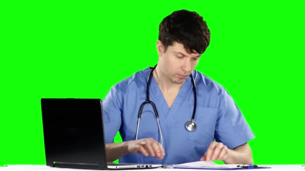 O médico toma notas enquanto toca no laptop. Tela verde — Vídeo de Stock