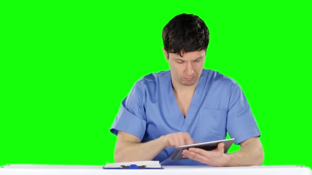 Il giovane medico usa una compressa e mostra il pollice verso il basso. Schermo verde — Video Stock