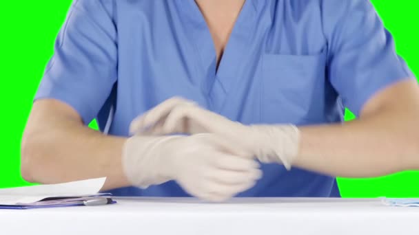 Мужчина снимает и надевает хирургические перчатки. Зеленый экран — стоковое видео