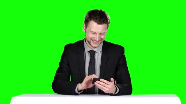 Бизнесмен сидит за столом и пользуется телефоном. Зеленый экран — стоковое видео