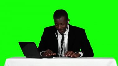 İşadamı bir masada oturuyor ve kulaklıkla müzik dinliyor. Yeşil ekran