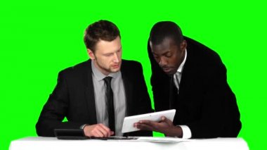 İki başarılı işadamı ofisteki müzakere masasına oturup dizüstü bilgisayarında çalışıyor. Yeşil ekran.