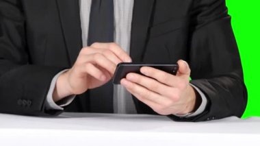 Masada oturan işadamı telefon kullanıyor. Closeup. Yeşil ekran