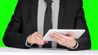 Resmi takım elbiseli kişi masada oturur ve dizüstü bilgisayar kullanır. Yeşil ekran