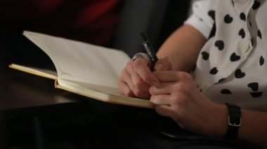Bir kalem ve defter bir seminer etkinlikte tutan kadın.