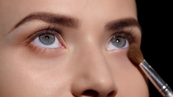 Makeup artist tillämpa ögonskugga på ögonlocket. Svart. Närbild — Stockvideo