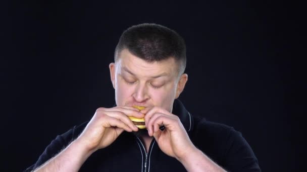 Man een cheeseburger eten. Zwart. Slow motion — Stockvideo