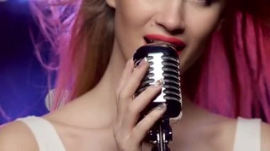Woman singing close-up: mouth and hands touch the vintage microphone