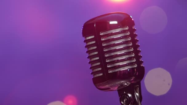 Microphone rétro contre l'éclairage de scène violet flou avec confettis paillettes — Video