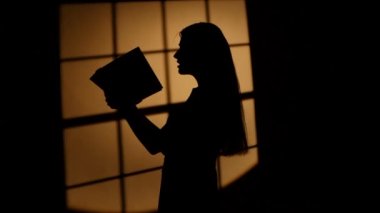 Profilinde poz veren bir kitap olan kız. Odak dinamik değişimi
