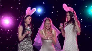 Kız arkadaşlar bekarlığa veda partisinde dans edip şampanya içiyorlar. Yavaş çekim