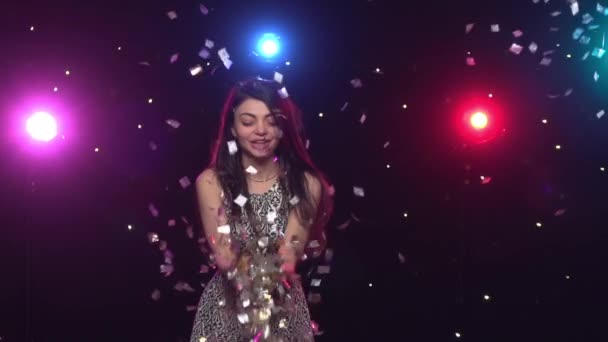 Young woman blowing with hands glitter confetti. Slow motion