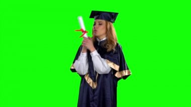 Mezun bir diploma tutarak ve onu öper. Yeşil ekran. Yavaş çekim