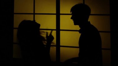 Pencerenin yanında kız ve oğlan var. Siluet. Yakın çekim