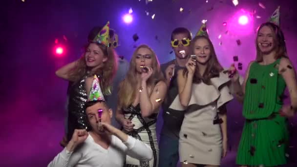 Mujeres jóvenes hombres bailando y soplando silbato de fiesta. Movimiento lento — Vídeos de Stock