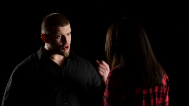 Emotional man with woman says irritably on black background. Close-up — Stock Video