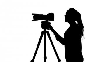 Operatör bir tripod üzerinde kamera ile çekim yapar. Beyaz. Siluet