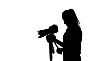 Operatör bir tripod ile çekim yapar. Beyaz. Siluet