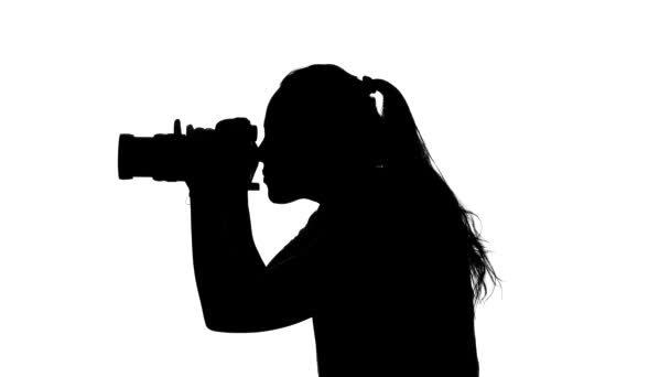 Фотограф работает с камерой в студии. Белый. Силуэт
