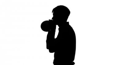 Adam bir hava balonu şişiriyor ve onu bağlıyor. Siluet. Beyaz