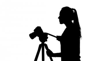 Fotoğrafçı bir tripod ile çalışır. Beyaz. Siluet