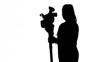 Operatör bir tripod ile stüdyoda çalışıyor. Beyaz. Siluet
