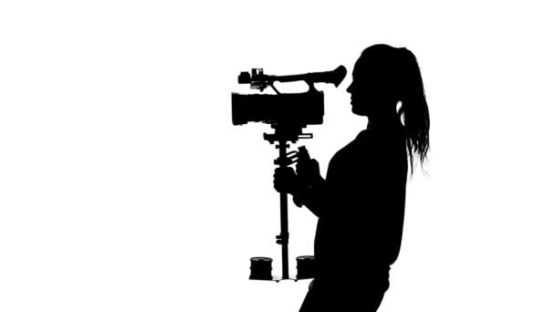 Videographer shoots video in the studio. White. Silhouette — Stock Video