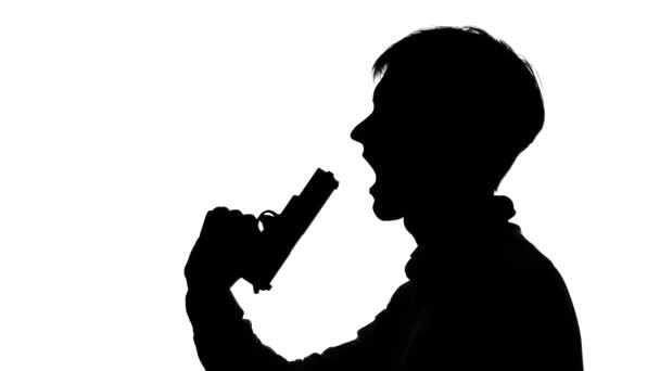 Un uomo gli punta una pistola alla bocca. Silhouette. Bianco — Video Stock
